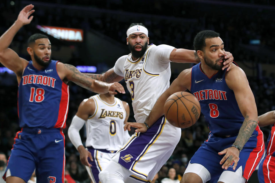 Los Angeles Lakers forward Anthony Davis, center, gets a piece of Detroit Pistons forward Trey Lyles, right, knocking the ball away with guard Cory Joseph, left, looking on during the first half of an NBA basketball game Sunday, Nov. 28, 2021, in Los Angeles. (AP Photo/Alex Gallardo)