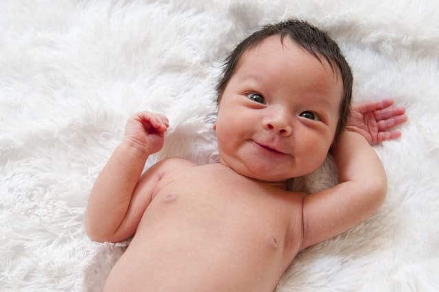 Happy newborn baby making a funny face.