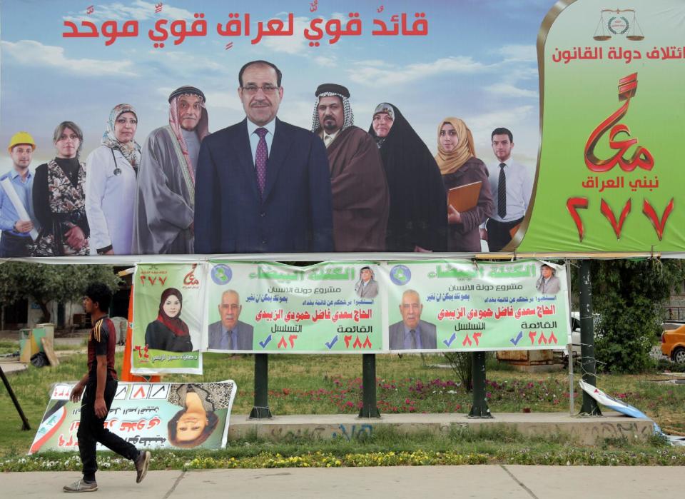 FILE - In this file photo taken on April 27, 2014 a man passes by a campaign poster of Iraqi Prime Minister Nouri al-Maliki, top, in Baghdad, Iraq. If Iraqi Prime Minister Nouri al-Maliki wins a third four-year term in parliamentary elections Wednesday, he is likely to rely on a narrow sectarian Shiite base, only fueling divisions as Iraq slides deeper into bloody Shiite-Sunni hatreds. (AP Photo/Khalid Mohammed, File)