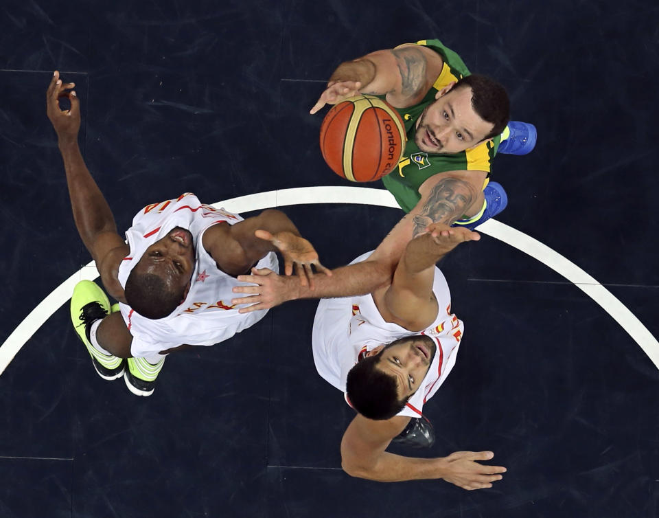 Brazil's Caio Torres (R) and Spain's Felipe Reyes and Serge Ibaka (L) reach for the rebound during their men's preliminary round Group B basketball match at the Basketball Arena during the London 2012 Olympic Games August 6, 2012. REUTERS/Sergio Perez (BRITAIN - Tags: OLYMPICS SPORT BASKETBALL) 