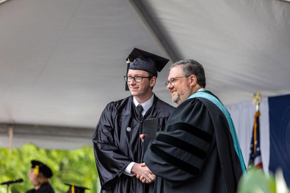 Dr. Darrin Hartness, president of Davidson-Davie Community College, poses for a picture with a graduate as he receives his diploma during a commencement ceremony at the college on Thursday.