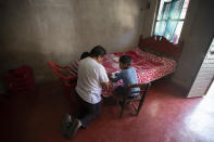 Using a bed as a desk, Agustin Vazquez helps his sons Samuel and Hector with their schoolwork handed out by teachers amid the new coronavirus pandemic at their home in Nuevo Yibeljoj, Chiapas state, Mexico, Friday, Sept. 11, 2020. “I try, but it’s not the same as a teacher, because I’m a farmer,” said Agustín. (AP Photo/Eduardo Verdugo)