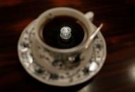 A jewelry-shaped lamp on the ceiling is reflected on a cup of coffee at Shizuo Mori's Heckeln coffee shop in Tokyo