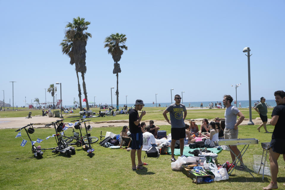 People stand next to a grill as they spend the day on a park during Israel's Independence Day celebrations in Tel Aviv, Tuesday, May 14, 2024. Israelis are marking 76 years since Israel's creation. (AP Photo/Ohad Zwigenberg).