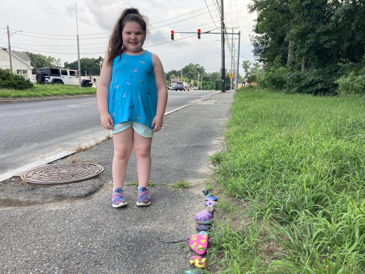 Lucy Lacombe poses next to her rocks after adding her latest creations to Jake the Snake's tail.