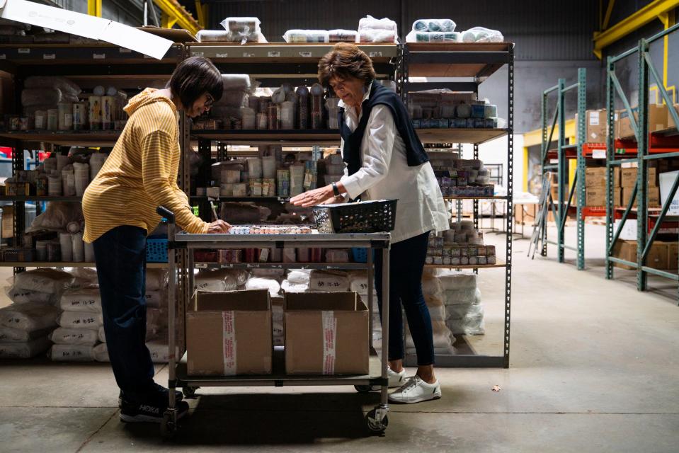 Kim Mitchell, 55, of Detroit, left, and Becky Riess, of Sylvan Lake, co-owner of Thumbprint Artifacts, prepare an online order of hand poured and hand painted candles at the company's warehouse in Detroit on Wednesday, Nov. 2, 2022.