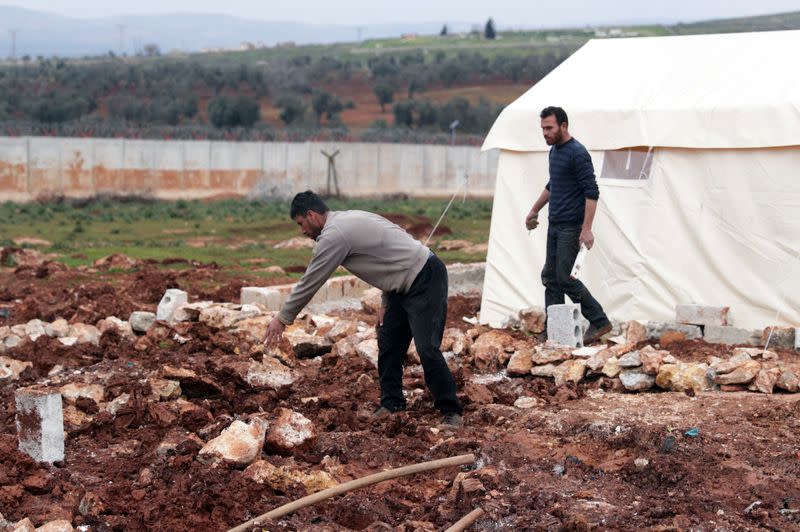 Internally displaced Syrians put up a tent near the wall in Atmah IDP camp, located near the border with Turkey