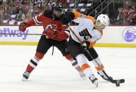 Philadelphia Flyers left wing Scott Laughton (21) skates with the puck as he is checked by New Jersey Devils defenseman P.K. Subban (76) during the first period of an NHL hockey game Sunday, Nov. 28, 2021, in Newark, N.J. (AP Photo/Bill Kostroun)