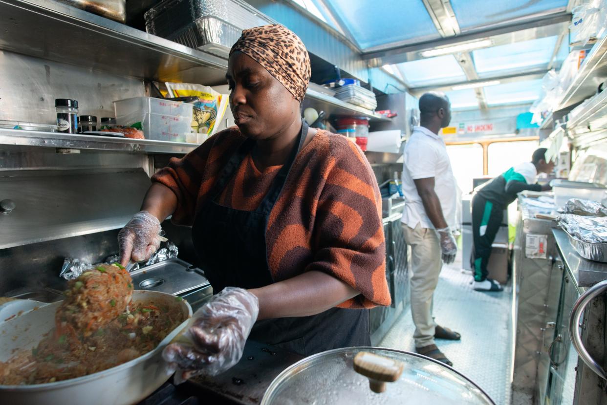 Millicent Twum-Barimah, left, stirs her signature shrimp fried rice as her husband Isaac, middle, and 14-year-old son Eric take orders Thursday in NOTO. Twum-Barimah started KononiaTouch African Cuisine a little over a year ago out of her church kitchen and several months ago opened a food truck.