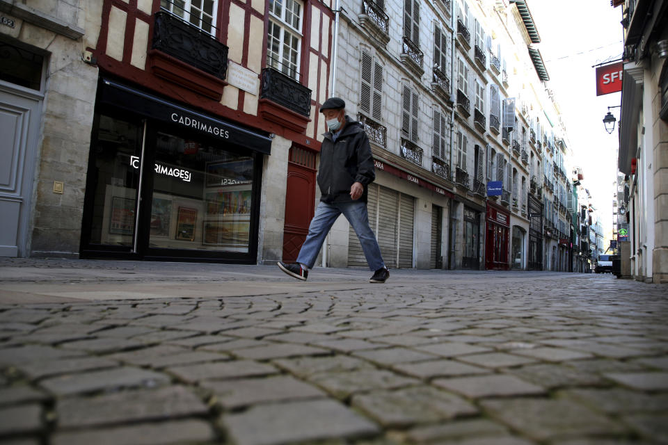 A man walks in an empty street during a nationwide confinement to counter the Covid-19, in Bayonne, southwestern France Friday, Oct. 30, 2020 . France re-imposed a monthlong nationwide lockdown Friday aimed at slowing the spread of the virus, closing all non-essential business and forbidding people from going beyond one kilometer from their homes except to go to school or a few other essential reasons. (AP Photo/Bob Edme)