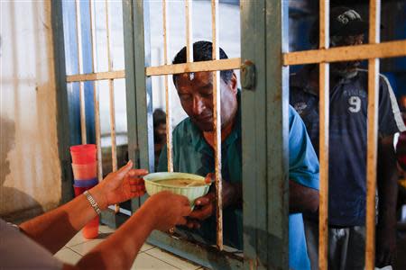 A voluntary worker gives a bowl of soup to a man at the Mother Teresa of Calcutta eating center in Caracas March 17, 2014. REUTERS/Carlos Garcia Rawlins