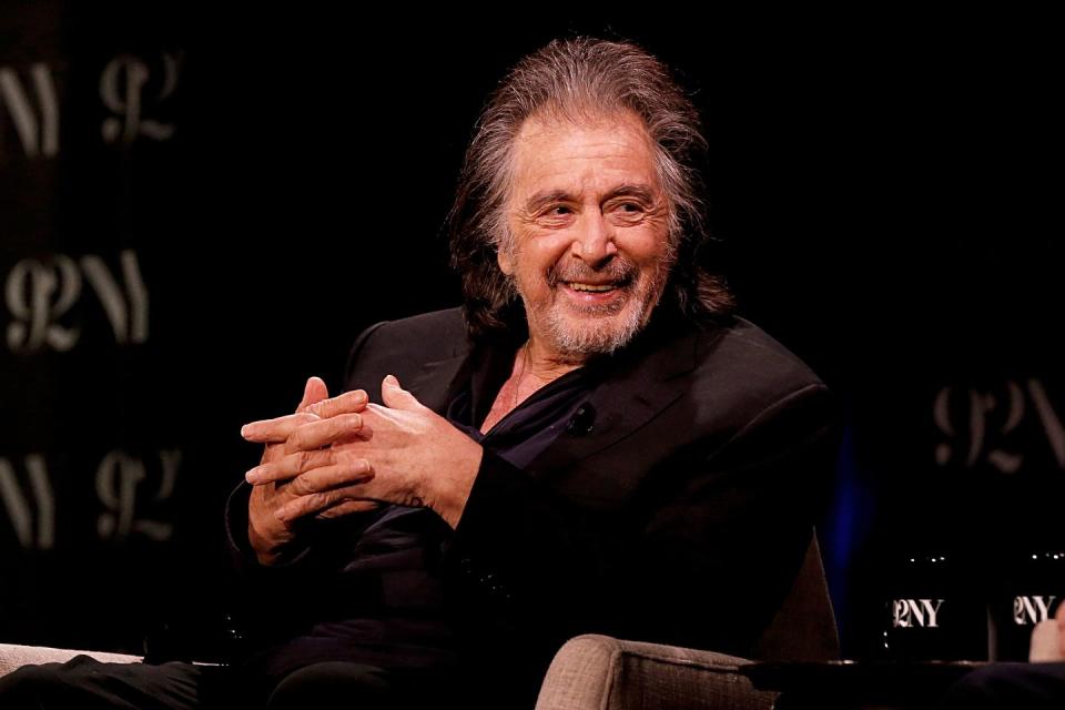 al pacino looking to his left and smiling as he speaks to a panel reporter