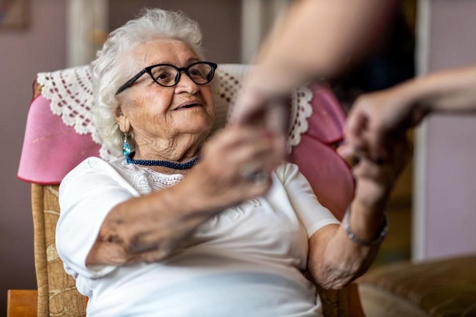 elderly woman holds hands of carer