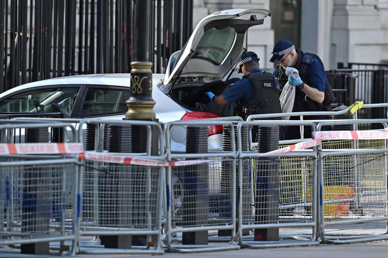 Los agentes de policía miran los artículos en el maletero de un automóvil que fue conducido a las puertas del número 10 de Downing Street, la residencia oficial del primer ministro británico, en el centro de Londres el 25 de mayo de 2023.