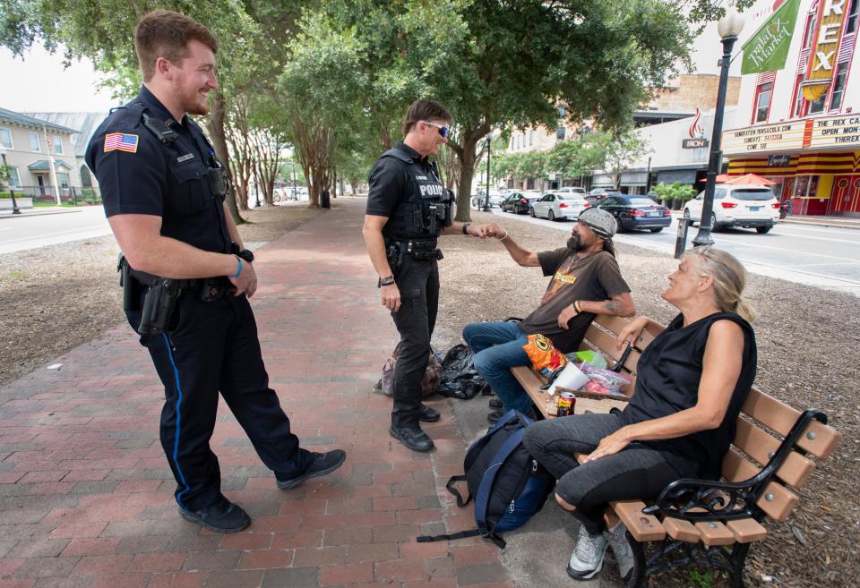 From left, officers David Partrick and Kenneth McMahon, of the Pensacola Police Department Community Outreach Division, chat with Earl Wollitz and Rosanna White in Dr. Martin Luther King Jr. Plaza in downtown Pensacola on Tuesday, July 19, 2022. The Pensacola Police Department plans to hire two new mental health experts to help deescalate mental health emergencies.