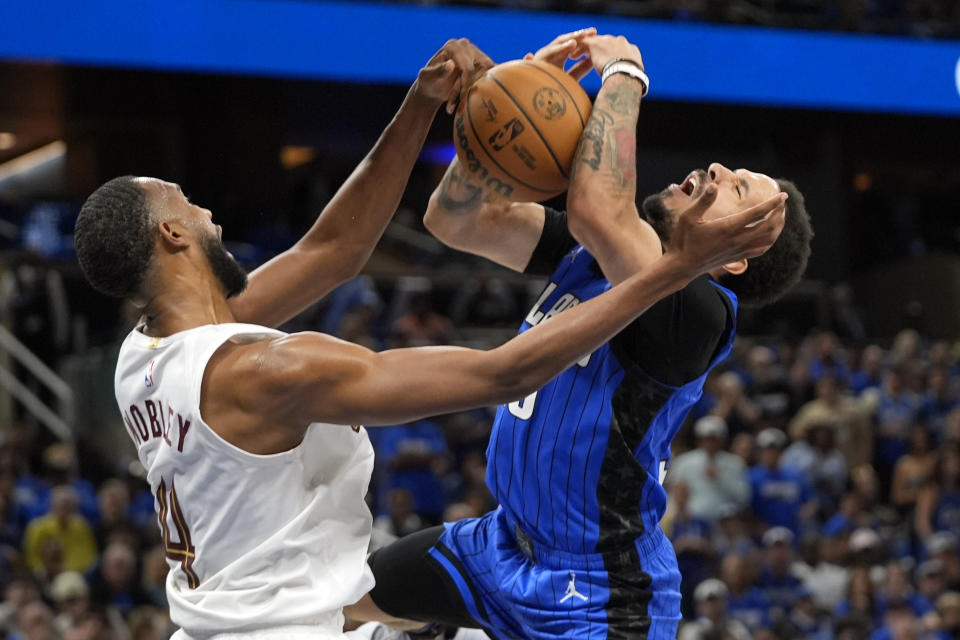 Cleveland Cavaliers forward Evan Mobley (left) faces Orlando Magic guard Cole during the second half of Game 6 of the first round of the NBA basketball playoff series on Friday, May 3, 2024 in Orlando, Florida. -Anthony fouls while trying to take a shot.  (AP Photo/John Rau)