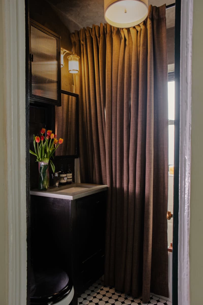 bathroom with brown curtain and warm light with fresh tulips by the sink