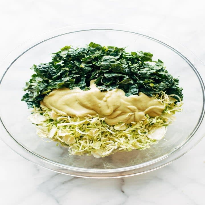 Kale and Brussels sprouts in a bowl with dressing.