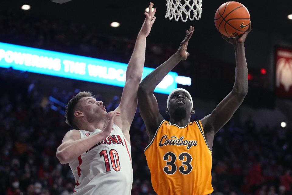 Wyoming forward Graham Ike (33) shoots next to Arizona forward Azuolas Tubelis during the first half of an NCAA college basketball game Wednesday, Dec. 8, 2021, in Tucson, Ariz. (AP Photo/Rick Scuteri)