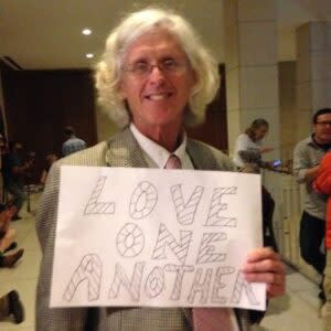 Patrick O'Neill holding a sign that read "Love one another"