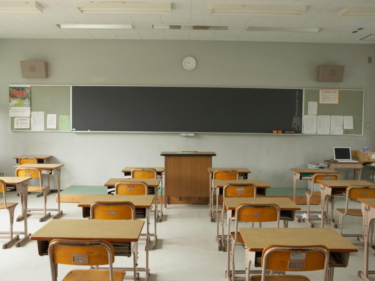 View of desks from the back of an empty classroom facing a chalkboard