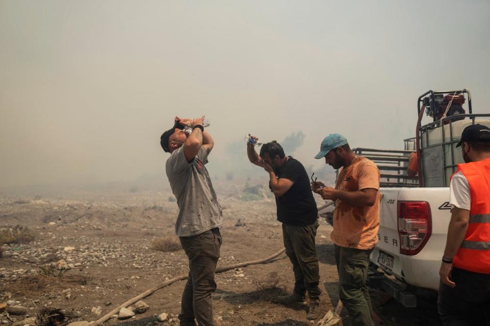 Volunteers cool themselves during a wildfire in Vati village, on the Aegean Sea island of Rhodes (AP)