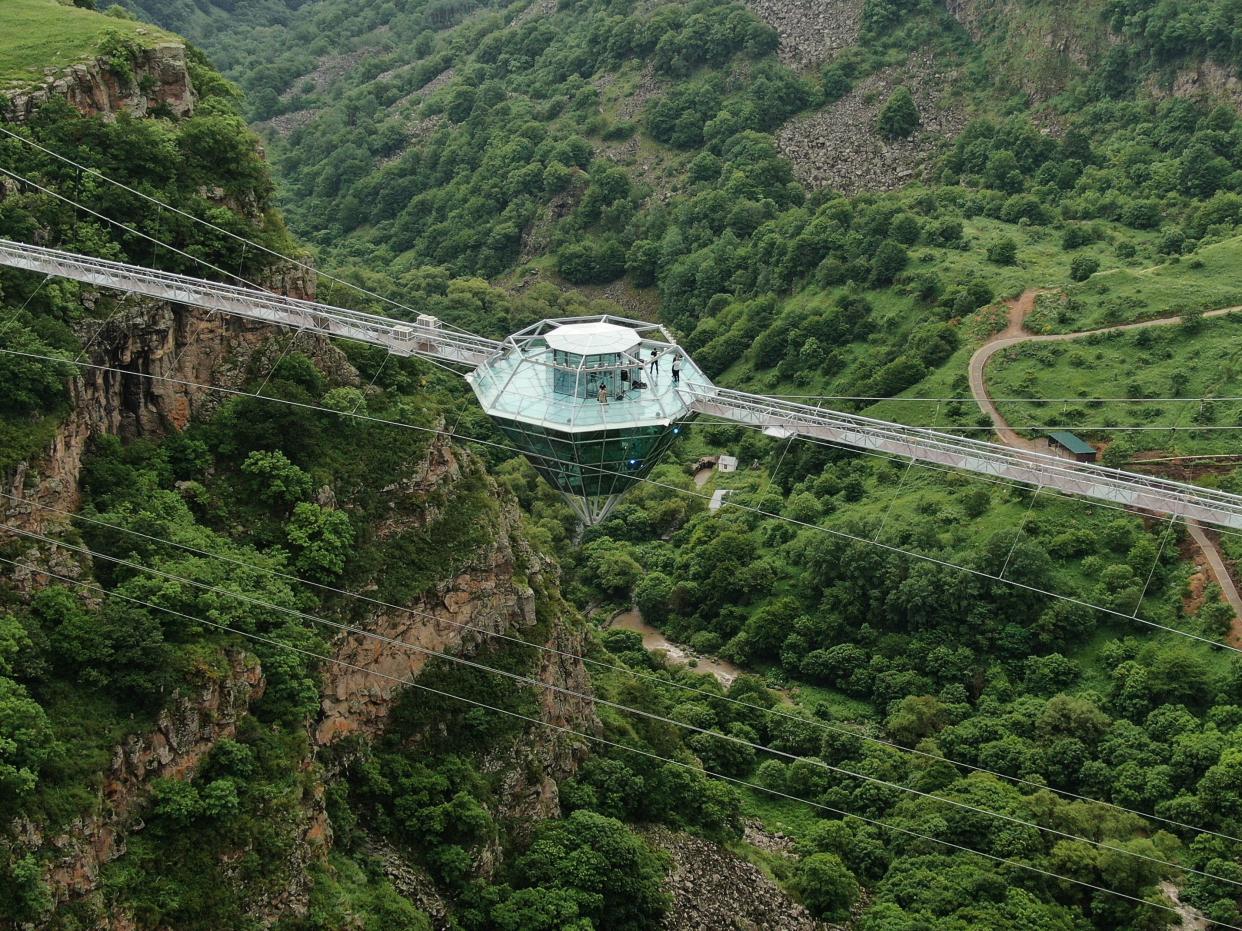 a glass bar suspended in the air in the middle of a glass bridge above Dashbashi Canyon in the country of Georgia