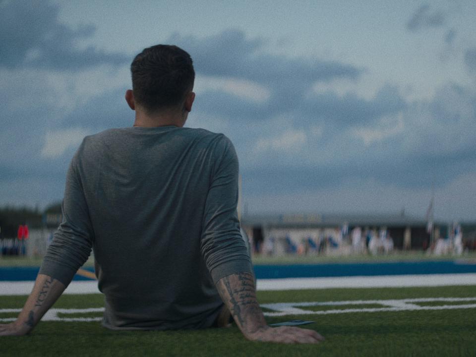 Johnny Manziel sits and looks out at his high school football field.