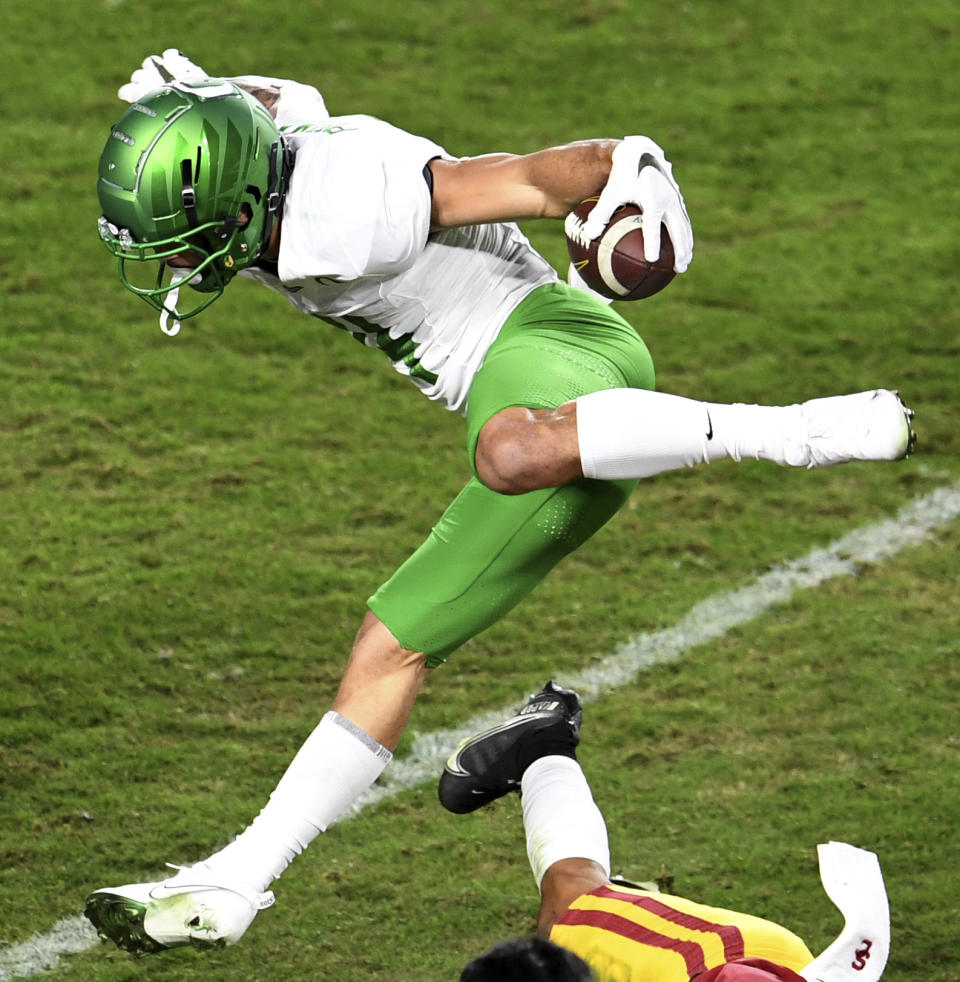 Oregon wide receiver Mycah Pittman catches a pass and leaps over USC cornerback Chris Steele for a first down in the first half of an NCAA college football game at the Los Angeles Memorial Coliseum in Los Angeles on Friday, Dec. 18, 2020. (Keith Birmingham/The Orange County Register via AP)