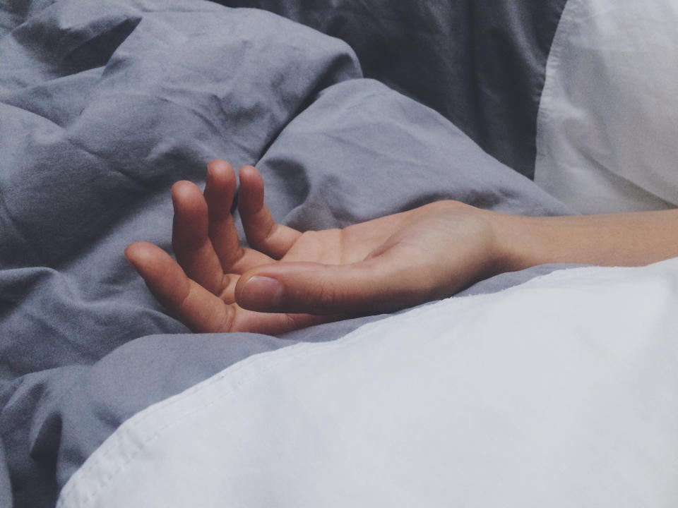 a person's hand lying on a bed