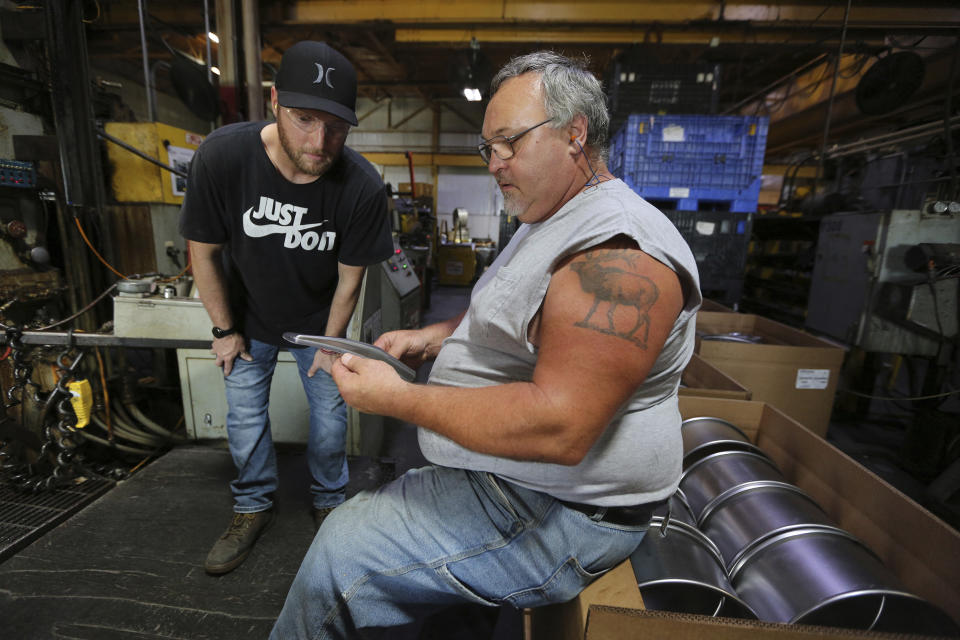 In this Friday, July 2, 2021, photo, press operator Zachary Carr, left, looks over a part with long-time employee Walter Rupert at Uelner Precision Tools & Dies in Dubuque, Iowa. (Dave Kettering/Telegraph Herald via AP)