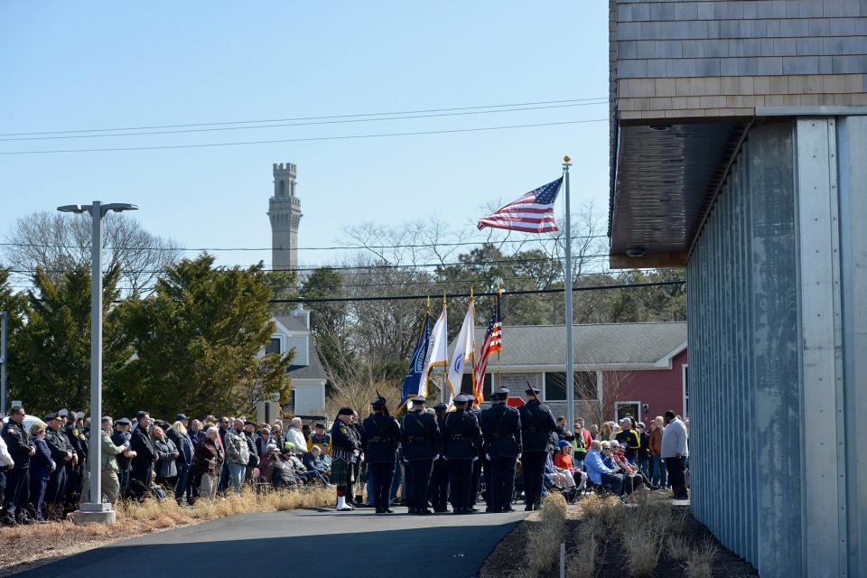 With the Pilgrim Monument as a backdrop, the flags held by the Provincetown Police Department honor guard flap in the breeze Wednesday at the new police station, set to open April 4. The American flag was also raised for the first time at the new station.