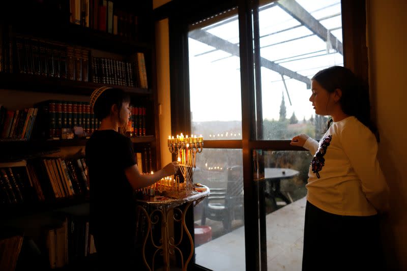 A boy of the Orbach family lights a hanukkiyah, a candlestick with nine branches that is lit to mark Hanukkah, the 8-day Jewish Festival of Lights, at their home in the Jewish settlement of Tekoa, in the Israeli-occupied West Bank