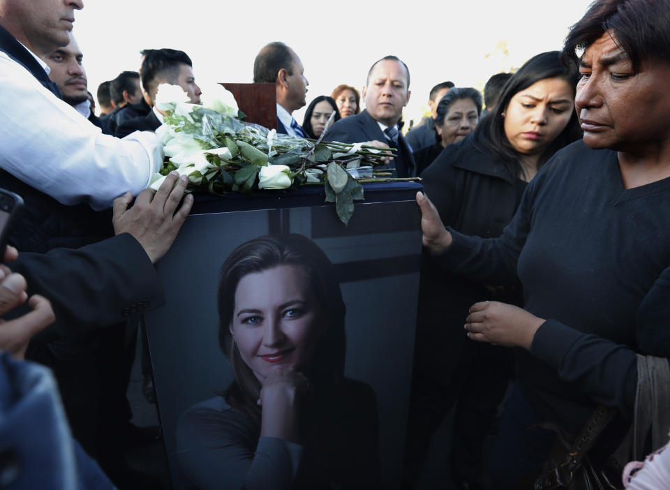 Relatives and friends surround the urn with ashes of opposition Puebla state Gov. Martha Erika Alonso during a farewell ceremony in Puebla City, southeast of Mexico, Tuesday, Dec. 25, 2018. Mexico has invited experts from the U.S. National Transportation Safety Board to investigate a helicopter crash that killed the governor, her husband, two pilots and a third passenger. (AP Photo/Marco Ugarte)