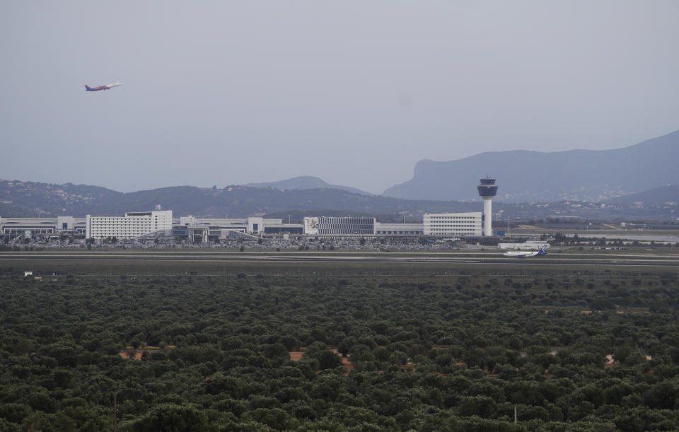 A plane takes off as the olive groves surround the city's international airport, in Spata suburb, east of Athens, Greece, Friday, Nov. 3, 2023. Across the Mediterranean, warm winters, massive floods, and forest fires are hurting a tradition that has thrived for centuries. Olive oil production has been hammered by the effects of climate change, causing a surge in prices for southern Europe's healthy staple. (AP Photo/Thanassis Stavrakis)