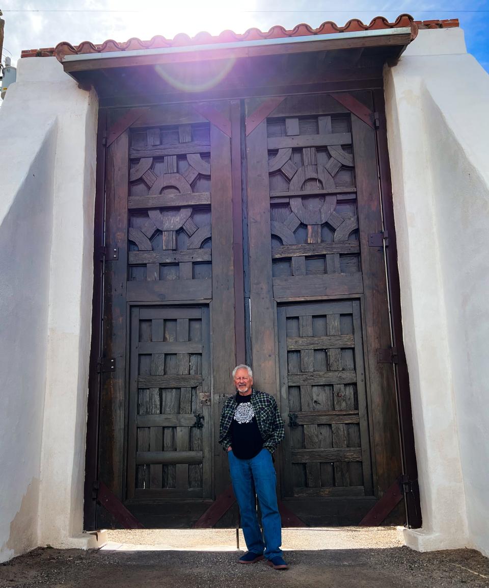 Artist Gaspar Enríquez stands in front of massive doors at his Micasa Art Studio and Gallery in San Elizario. The restored doors are from an old church in Mexico.