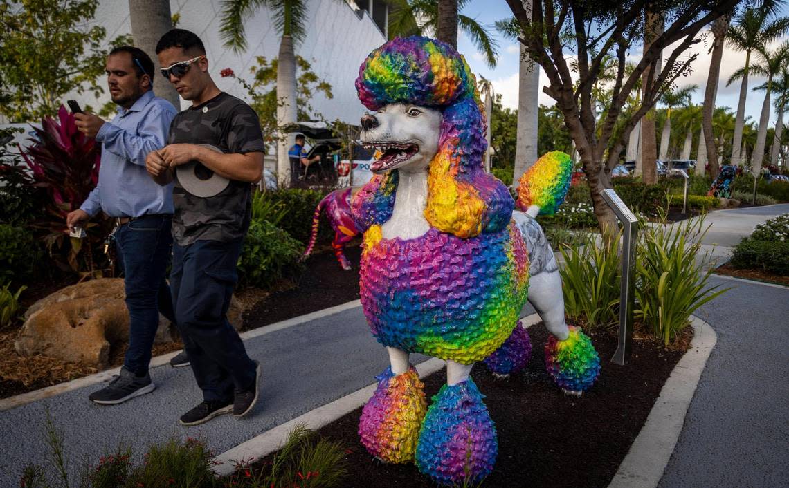 Two men walk past the statue of a Poodle at the Dogs and Cats Walkway and Sculpture Gardens at Maurice A. Ferré Park.