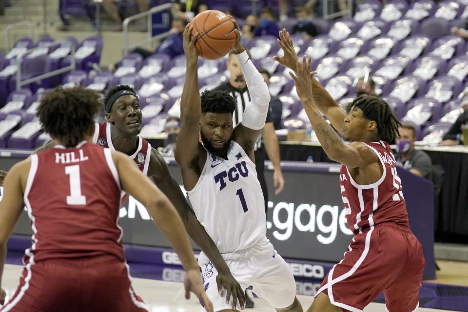 Oklahoma's Jalen Hill (1), Kur Kuath, left rear, and Alondes Williams (15) defend against a drive to the basket by TCU guard Mike Miles (1) in the second half of an NCAA college basketball game in Fort Worth, Texas, Sunday, Dec. 6, 2020. (AP Photo/Tony Gutierrez)