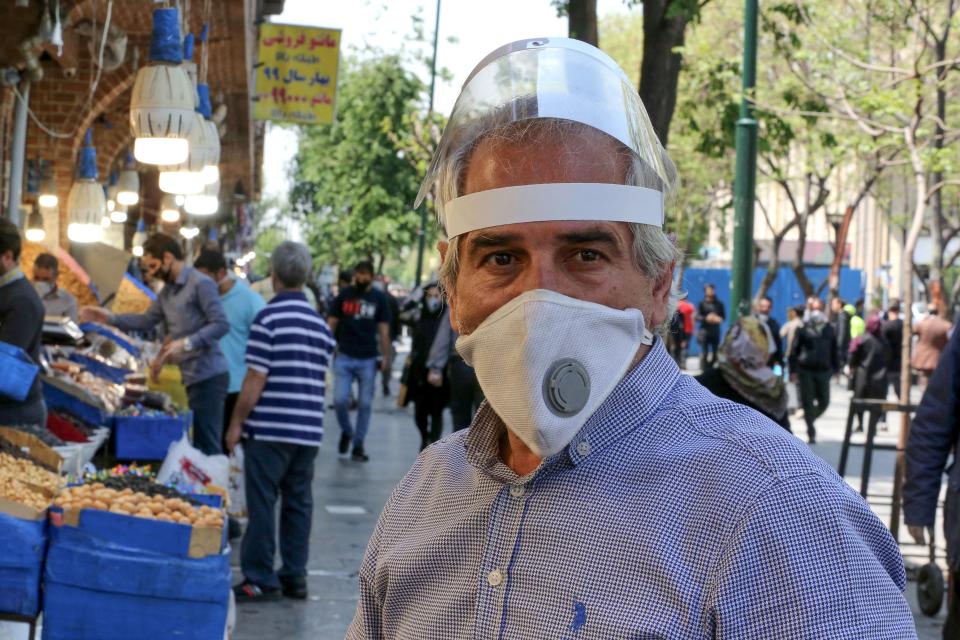 An Iranian man, wearing personal protective equipment amid the COVID-19 pandemic, shops at the Grand Bazaar market in the capital Tehran, on April 18, 2020. - Iran allowed some shuttered Tehran businesses to reopen on April 18 despite the Middle East's deadliest coronavirus outbreak, as many faced a bitter choice between risking infection and economic ruin. (Photo by ATTA KENARE / AFP) (Photo by ATTA KENARE/AFP via Getty Images)