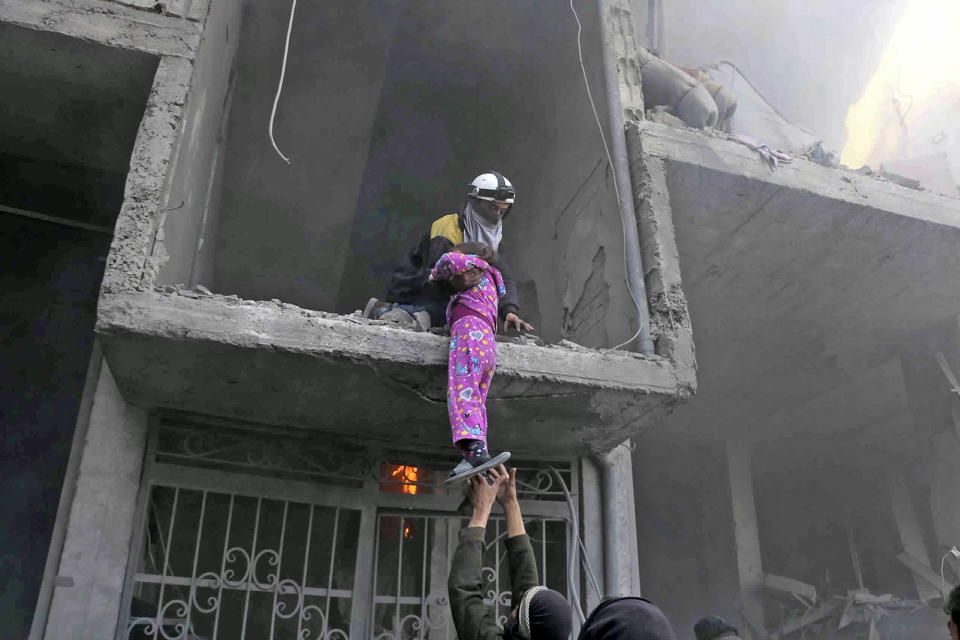 <p>A member of the Syrian Civil Defense group rescues a young girl from a building damaged by airstrikes and shelling by Syrian government forces, in Ghouta, a suburb of Damascus, Syria on Feb. 21, 2018. (Photo: Syrian Civil Defense White Helmets via AP) </p>