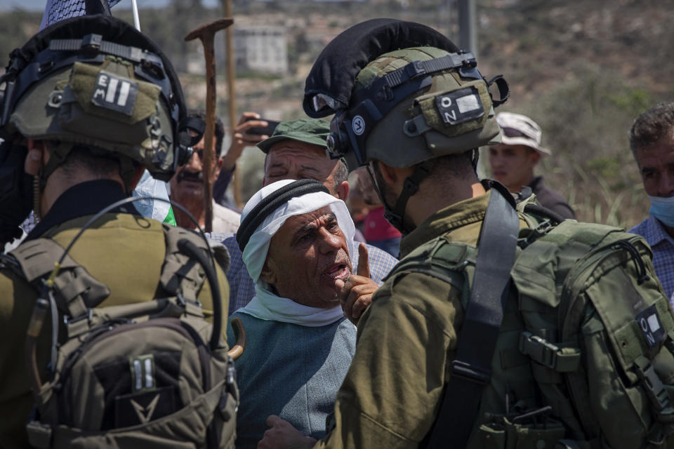 A Palestinian argues with Israeli soldiers during a protest against the creation of a new road for Israeli settlers, near the Palestinian village of Beita, north of the West Bank city of Nablus, Wednesday, Aug. 25, 2021. (AP Photo/Majdi Mohammed)