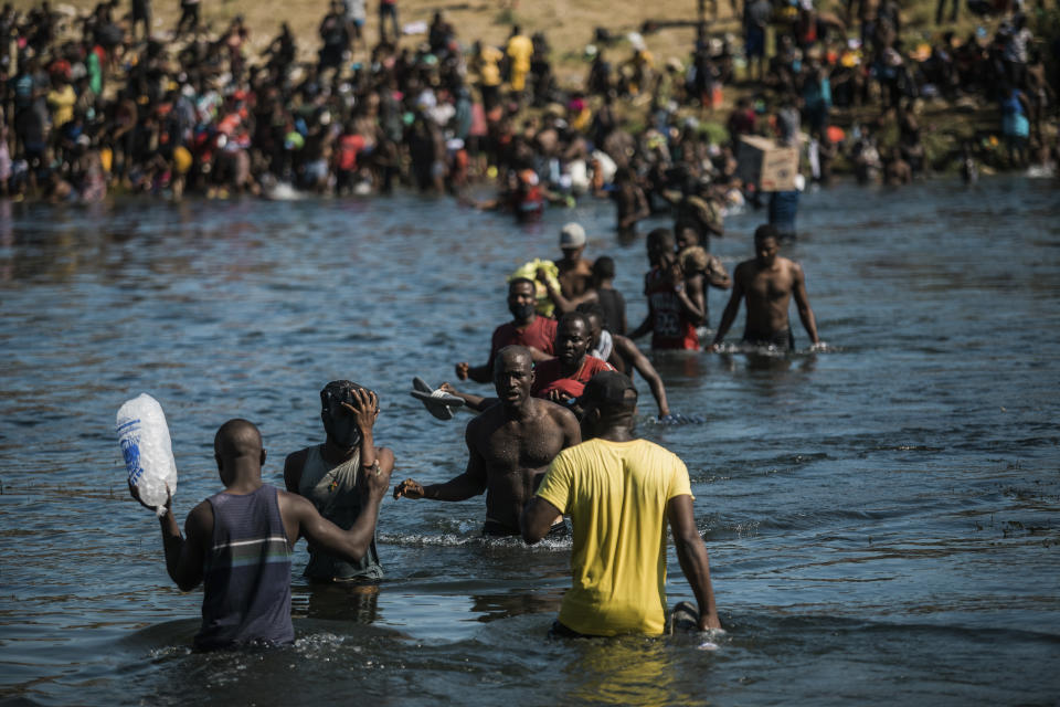 Migrants wade across the Rio Grande from Del Rio, Texas, to Ciudad Acuña, Mexico, to shop for food and supplies before returning back to the US side of the border, Sunday, Sept. 19, 2021. Thousands of Haitian migrants have been arriving to Del Rio, Texas, as authorities attempt to close the border to stop the flow of migrants. (AP Photo/Felix Marquez)