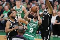 Boston Celtics' Derrick White (9) goes up to shoot against Brooklyn Nets' Bruce Brown (1) and Nic Claxton (33) during the first half of Game 2 of an NBA basketball first-round Eastern Conference playoff series Wednesday, April 20, 2022, in Boston. (AP Photo/Michael Dwyer)