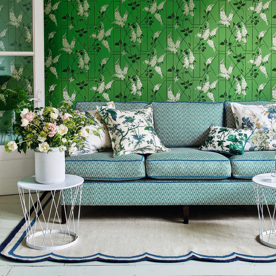 Living room with green wallpaper, grey sofa and scalloped rug.