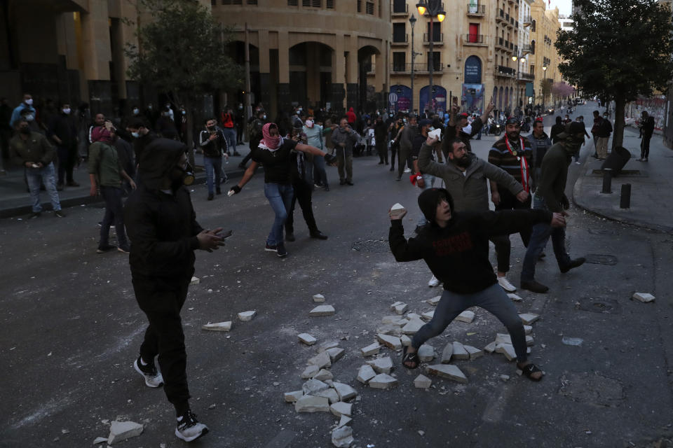 Anti-government protesters throw stones towards police near Parliament Square, In Beirut, Lebanon, Saturday, March. 13, 2021. Riot police fired tear gas to disperse scores of people who protested near parliament building in central Beirut Saturday amid deteriorating economic and financial conditions and as the local currency hit new low levels. (AP Photo/Bilal Hussein)