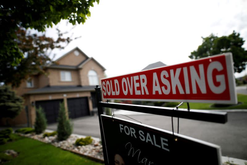 FILE PHOTO: A real estate sign that reads "For Sale" and "Sold Above Asking" stands in front of housing in Toronto