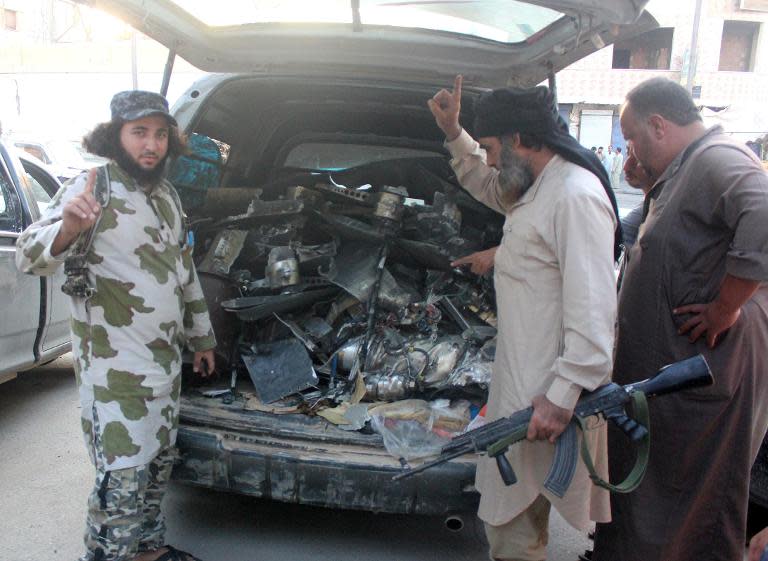 Fighters from the Islamic State group gesture as they load a van with parts that they said was a US drone that crashed into a communications tower in Raqqa early on September 23, 2014