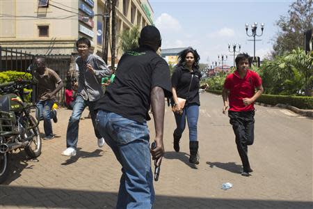 An armed security officer assists civilians escaping from the Westgate Shopping Centre where gunmen went on a shooting spree, in Nairobi