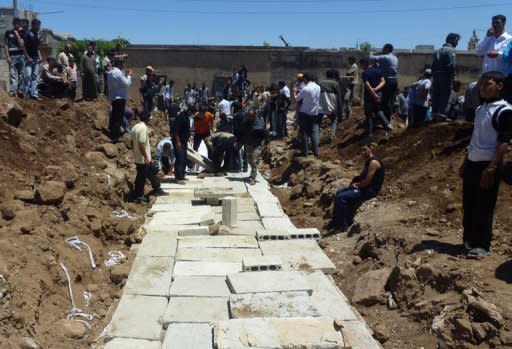 People watch the May 26 mass burial of more than 100 victims of the Houla massacre in Syria. Syrian President Bashar al-Assad has denounced those who committed the Houla massacre as "monsters" in a speech before parliament