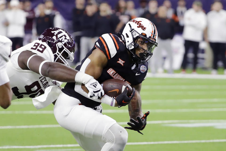 Oklahoma State running back Ollie Gordon II, right, is caught by Texas A&M defensive lineman Gabriel Brownlow-Dindy (99) during the first half of the Texas Bowl NCAA college football game Wednesday, Dec. 27, 2023, in Houston. (AP Photo/Michael Wyke)